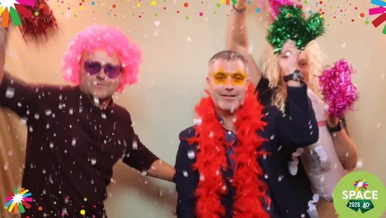 Trois invités en perruques et boas posent sous les confettis